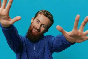 Portrait of a man in a sweater smile and happiness, hand signs and symbols, on a blue background. Lifestyle positive, copy place. photo