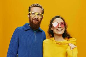 Man and woman couple smiling cheerfully and crooked with glasses, on yellow background, symbols signs and hand gestures, family shoot, newlyweds. photo