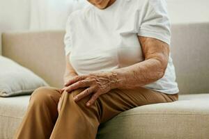 mayor mujer grave cofre dolor sentado en el sofá, salud problemas en antiguo edad, pobre calidad de vida. abuela con gris pelo sostiene su cofre con su manos, De las mujeres salud, pecho cáncer. foto