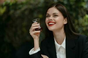 Woman smile with teeth drinking tea in a cafe from a Turkish glass mug on the street, spring travel, city break photo