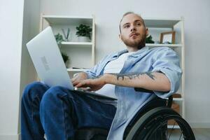 Man wheelchair freelancer working at laptop at home smile, working online, social networks and startup, copy space, integration into society, health concept man with disabilities, real person close-up photo