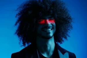 Fashion portrait of a man with curly hair on a blue background with a red stripe of light, multicolored light, trendy, modern concept. photo