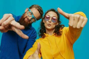 un mujer y un hombre divertido Pareja arrancando y demostración señales con su manos sonriente alegremente, en un azul fondo, el concepto de un real relación en un familia. foto