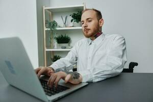 A man in a wheelchair a businessman with tattoos in the office works at a laptop, integration into society, the concept of working a person with disabilities, freedom from social frameworks photo