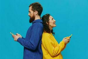 Woman and man cheerful couple with phones in their hands crooked smile cheerful, on blue background. The concept of real family relationships, talking on the phone, work online. photo