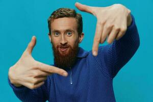 Portrait of a man in a sweater smile and happiness, hand signs and symbols, on a blue background. Lifestyle positive, copy place. photo