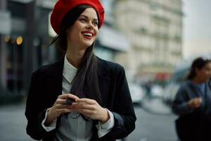 mujer sonrisa con dientes turista camina camina en el ciudad en el antecedentes de oficina edificios, elegante de moda ropa y constituir, primavera caminar, viajar. foto