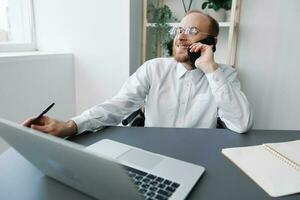 A man in a wheelchair businessman with tattoos in the office works, talking on the phone and smiling, integration into society, the concept of working a person with disabilities photo
