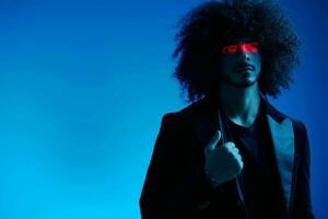 Fashion portrait of a man with curly hair on a blue background with a red stripe of light, multicolored light, trendy, modern concept. photo