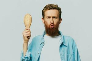 Portrait of a man with a massage comb in his hands, combing his hair and beard, hair loss problem photo