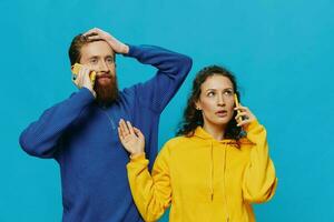 Woman and man cheerful couple with phones in their hands crooked smile cheerful, on blue background. The concept of real family relationships, talking on the phone, work online. photo