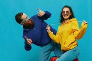 Woman and man smile sitting on suitcase with red suitcase smile, on blue background, packing for trip, family vacation trip. photo