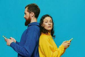 Woman and man cheerful couple with phones in their hands crooked smile cheerful, on blue background. The concept of real family relationships, talking on the phone, work online. photo
