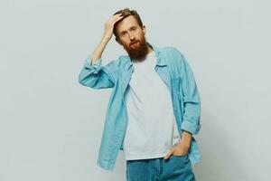 Male hipster portrait smile on gray background in blue shirt and white t-shirt, portrait of a man with a beard photo