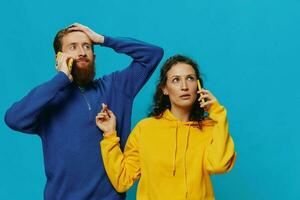 Woman and man cheerful couple with phones in their hands crooked smile cheerful, on blue background. The concept of real family relationships, talking on the phone, work online. photo