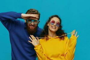 A woman and a man fun couple cranking and showing signs with their hands smiling cheerfully, on a blue background, The concept of a real relationship in a family. photo