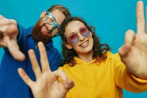 un mujer y un hombre divertido Pareja arrancando y demostración señales con su manos sonriente alegremente, en un azul fondo, el concepto de un real relación en un familia. foto