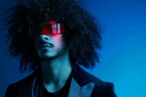 Fashion portrait of a man with curly hair on a blue background wearing red sunglasses, multinational, colored light, trendy, modern concept. photo
