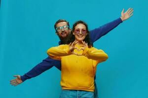 un mujer y un hombre divertido Pareja arrancando y demostración señales con su manos sonriente alegremente, en un azul fondo, el concepto de un real relación en un familia. foto