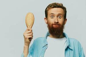 Portrait of a man with a massage comb in his hands, combing his hair and beard, hair loss problem photo