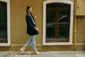 Woman blogger smile with teeth with a phone in her hands walks around the city fashion on the street, spring travel, vacation in the city tourist freelancer, mobile communication and internet for work photo