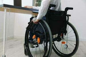 A man wheelchair businessman with tattoos in the office works at a laptop online, business process, a wheelchair close-up, integration into society, the concept of working a person with disabilities photo