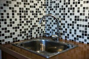 limpiar lavabo con torrencial agua en el cocina, metal grifo y lavabo en un antiguo hogar interior. foto