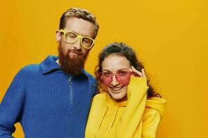 Man and woman couple smiling cheerfully and crooked with glasses, on yellow background, symbols signs and hand gestures, family shoot, newlyweds. photo