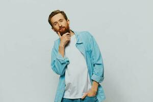 Male hipster portrait smile on gray background in blue shirt and white t-shirt, portrait of a man with a beard photo