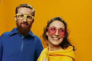 hombre y mujer Pareja sonriente alegremente y torcido con anteojos, en amarillo fondo, símbolos señales y mano gestos, familia disparar, recién casados. foto