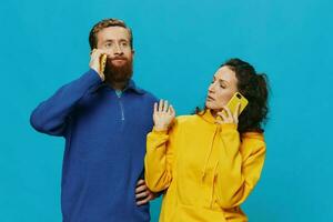 Woman and man cheerful couple with phones in their hands crooked smile cheerful, on blue background. The concept of real family relationships, talking on the phone, work online. photo