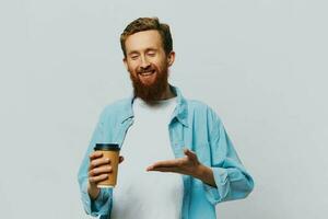 Man hipster with a cup of coffee with a smile on a gray background in a blue shirt and white t-shirt photo