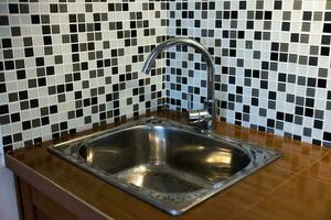 Clean sink with pouring water in the kitchen, metal faucet and sink in an old home interior. photo