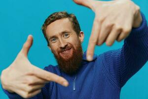 Portrait of a man in a sweater smile and happiness, hand signs and symbols, on a blue background. Lifestyle positive, copy place. photo