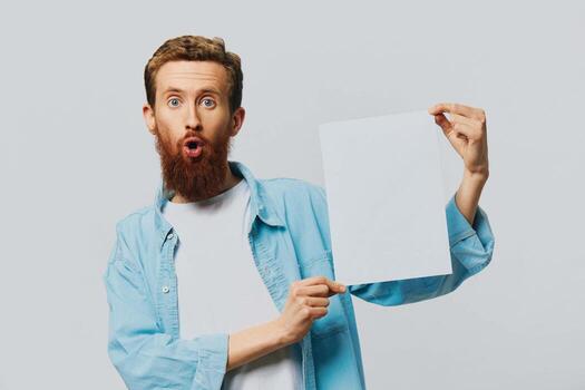 Portrait of an adult male on a gray background with a white sheet of paper in his hands for your design and text, layout, copy space, space for text, finger pointing photo