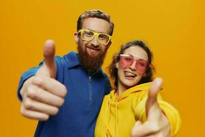 hombre y mujer Pareja sonriente alegremente y torcido con anteojos, en amarillo fondo, símbolos señales y mano gestos, familia disparar, recién casados. foto