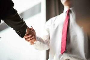 Close up of two business people shaking hands while sitting at the working place photo