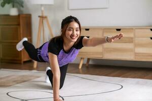 asiático mujer en Deportes vestir haciendo rutina de ejercicio a hogar con cardio. hogar ejercicio concepto. foto