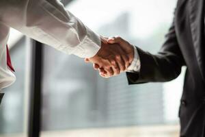 Close up of two business people shaking hands while sitting at the working place photo
