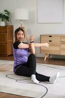 asiático mujer en Deportes vestir calentar arriba antes de rutina de ejercicio a hogar. hogar ejercicio concepto. foto