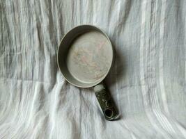 The gray frying pan is photographed on a white cloth background photo