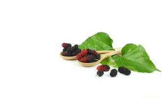 Healthy fruit - mulberry on wooden spoon with green leaves isolated on white photo