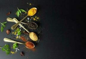 Top view of food background - Herbs and condiment on golden spoon against black background photo