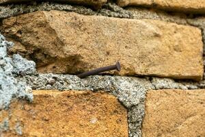 Old brickwall background. A nail hammered on red brickwall. photo