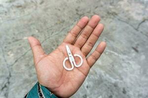 cute little scissors for kids playing. Small scissors on adult hand. photo