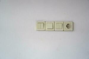 One socket and three switch. Electric socket and lamp switch button on the wall. photo