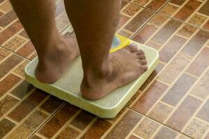 Standing on floor scale. Close up of man legs stapping on weight scales. photo