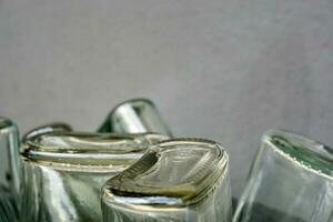 Closeup and crop of up side down and bottom of flat glass bottle on blurred gray background. photo