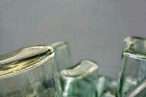 Closeup and crop of up side down and bottom of flat glass bottle on blurred gray background. photo