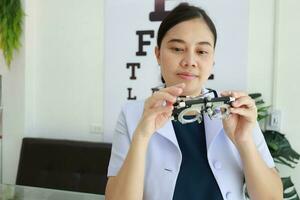 Female ophthalmologist holding eyeglasses inside clinic, eye doctor holding glasses in eyeglasses shop, Ophthalmologist holding eyeglasses in eyeglass clinic photo